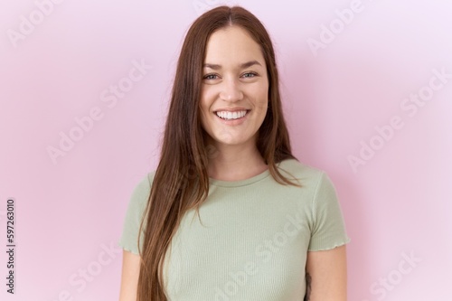 Beautiful brunette woman standing over pink background with a happy and cool smile on face. lucky person.