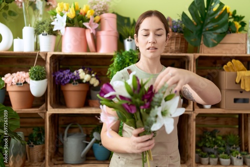 Young beautiful woman florist holding bouquet of flowers at flower shop