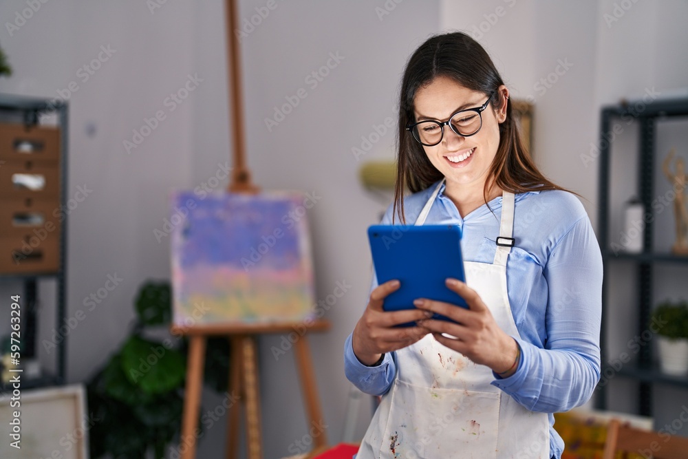 Young woman artist smiling confident using touchpad at art studio