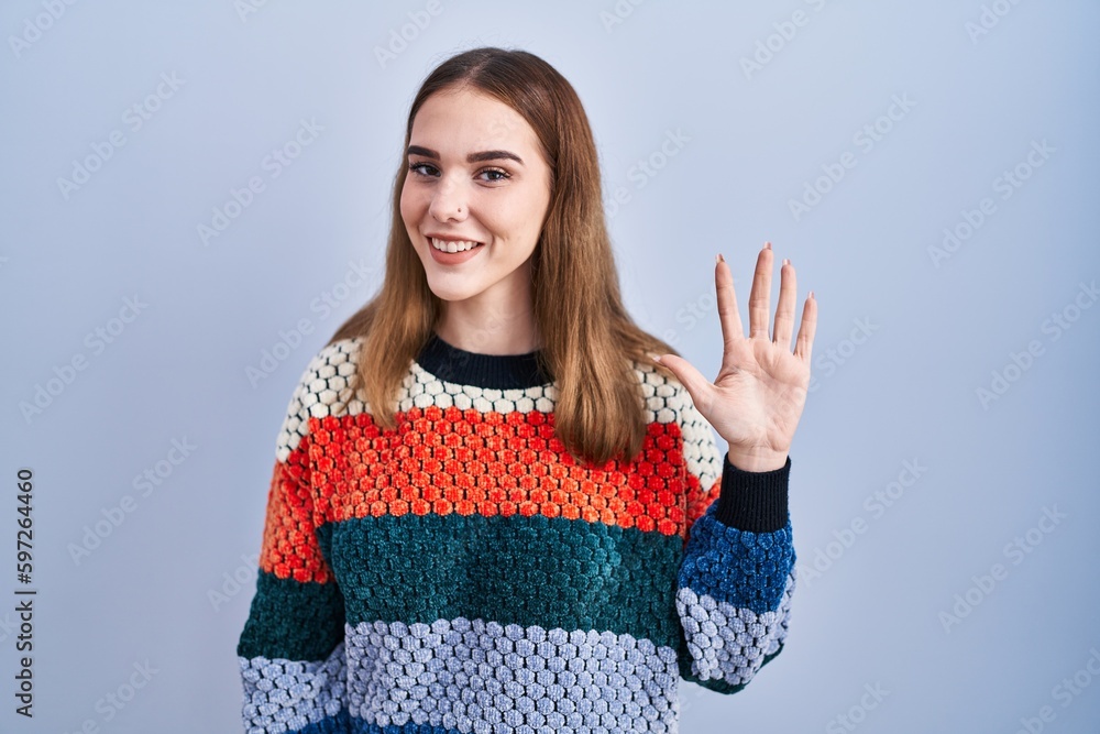 Young hispanic girl standing over blue background showing and pointing up with fingers number five while smiling confident and happy. Young hispanic girl standing over blue background showing and pointing up with fingers number five while smiling confident and happy.