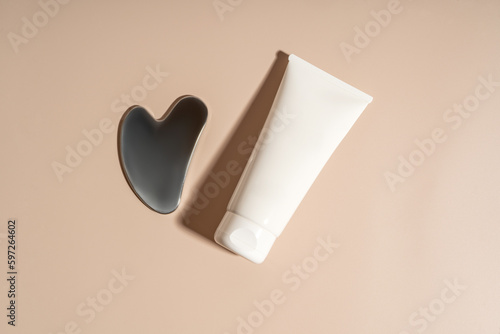 A face metal massager made of steal and a white tube of cream, product line presentation, marketing and branding