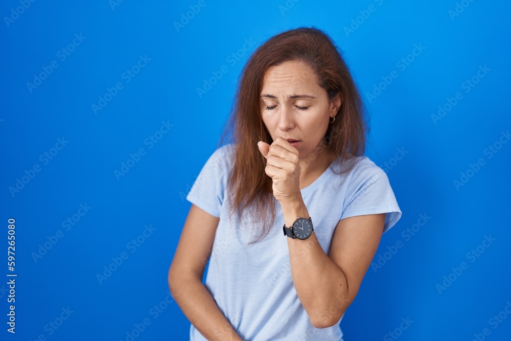 Brunette woman standing over blue background feeling unwell and coughing as symptom for cold or bronchitis. health care concept. Brunette woman standing over blue background feeling unwell and coughing as symptom for cold or bronchitis. health care concept.
