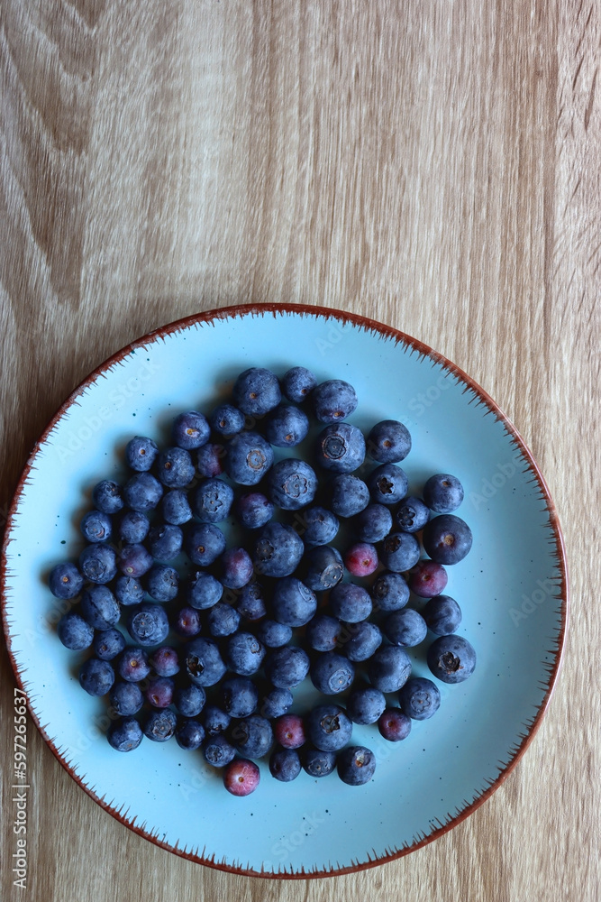 Turquoise plate with fresh blueberries on wooden background. Top view. Turquoise plate with fresh blueberries on wooden background. Top view.