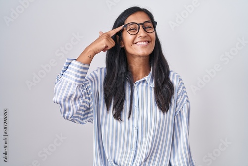 Young hispanic woman wearing glasses smiling pointing to head with one finger  great idea or thought  good memory