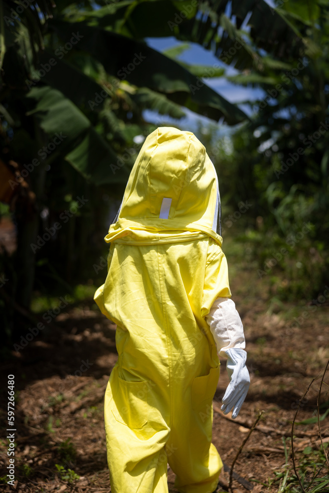 A kid in a protective suit walks to the apiary. A kid in a protective suit walks to the apiary.