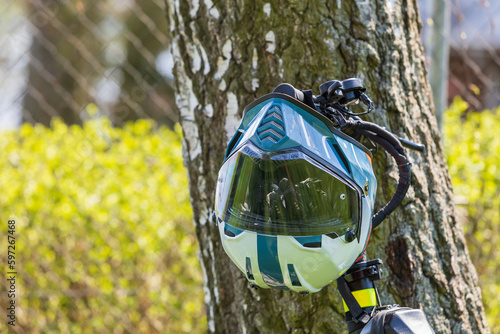 The motorcycle integral helmet is suspended from the handlebars of the electric scooter photo