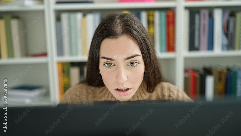 Young beautiful hispanic woman student using computer with serious expression at university classroom Young beautiful hispanic woman student using computer with serious expression at university classroom