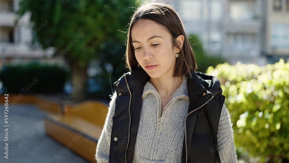 Young beautiful hispanic woman standing with serious expression at park