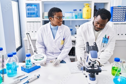 Man and woman scientists writing on notebook working at laboratory
