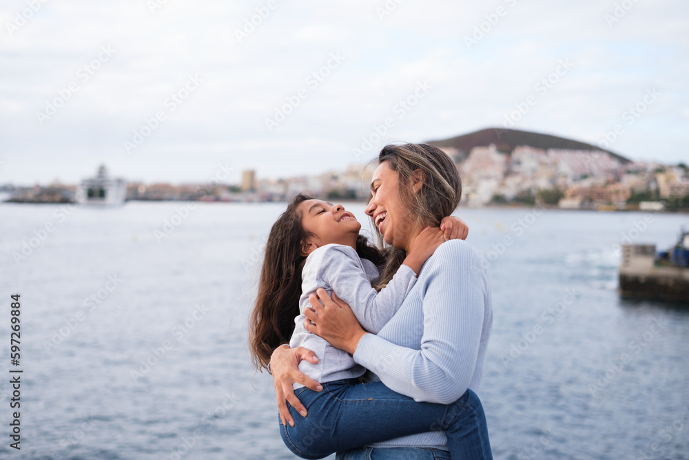 Mother and daughter hugging by the sea on a walk at sunset and sharing moments. Concept: lifestyle, motherhood, education