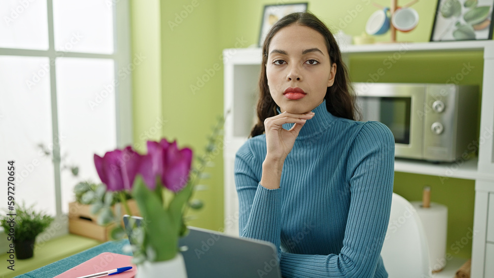Young beautiful hispanic woman using laptop sitting on table at home Young beautiful hispanic woman using laptop sitting on table at home