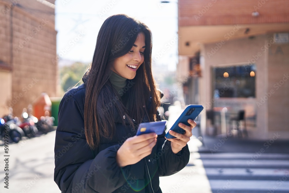 Young beautiful hispanic woman using smartphone and credit card at street Young beautiful hispanic woman using smartphone and credit card at street