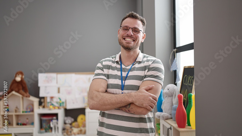 Young caucasian man working as teacher smiling with crossed arms at kindergarten © Krakenimages.com
