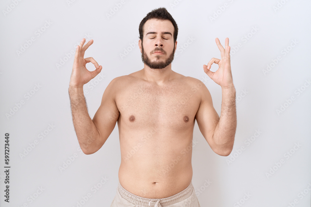 Young hispanic man standing shirtless over white background relax and smiling with eyes closed doing meditation gesture with fingers. yoga concept.
