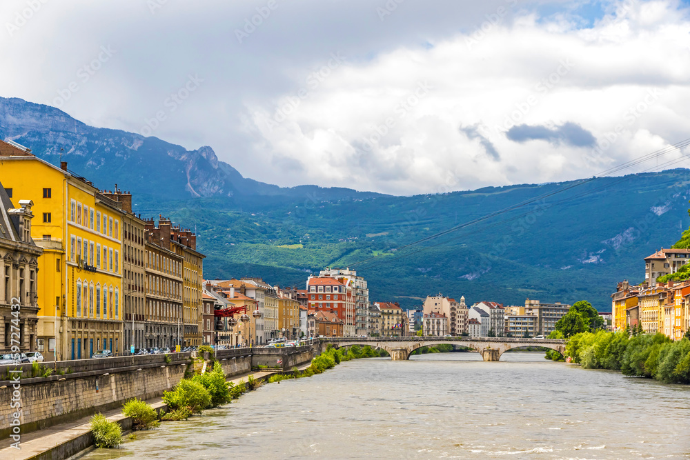 Isere river and Grenoble city skyline, Auvergne-Rhone-Alpes region, France. Pont Marius-Gontard bridge. Alps mountains on background