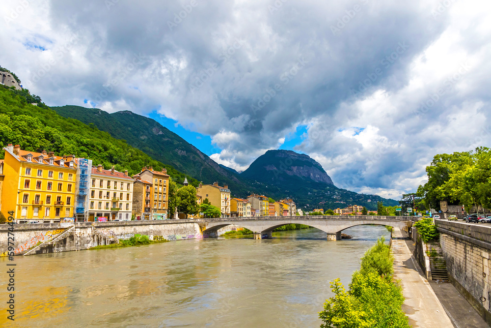 Isere river and Grenoble old town skyline, Auvergne-Rhone-Alpes region, France. Pont de la Citadelle bridge. Alps mountains on background