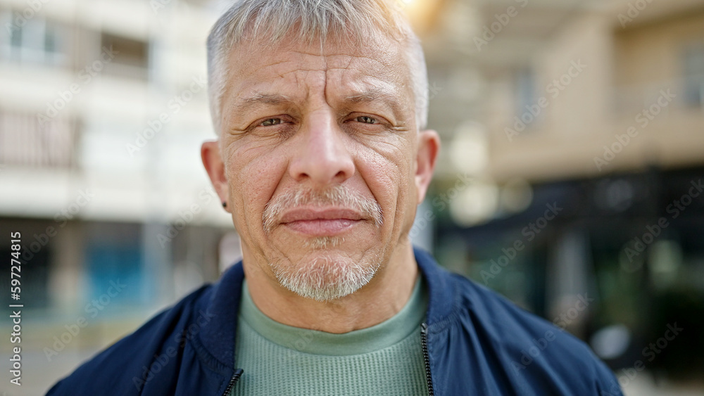 Middle age grey-haired man standing with serious expression at street Middle age grey-haired man standing with serious expression at street
