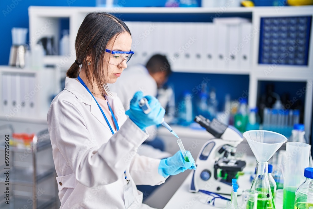 Man and woman scientists pouring liquid on test tube at laboratory Man and woman scientists pouring liquid on test tube at laboratory