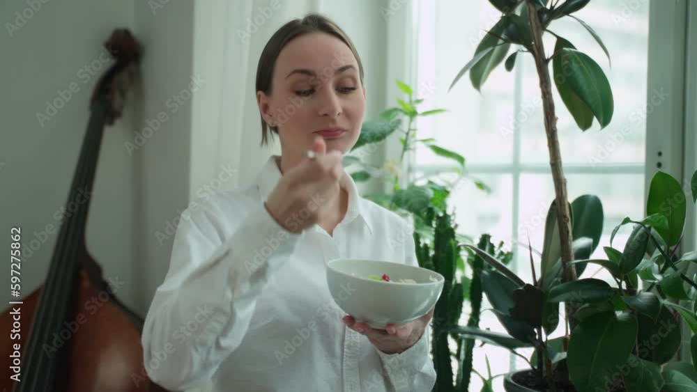 Young woman enjoys a delicious salad at home during the day. Portrait of a young and cheerful woman eating a healthy salad. The concept of healthy eating. Young woman enjoys a delicious salad at home during the day. Portrait of a young and cheerful woman eating a healthy salad. The concept of healthy eating.