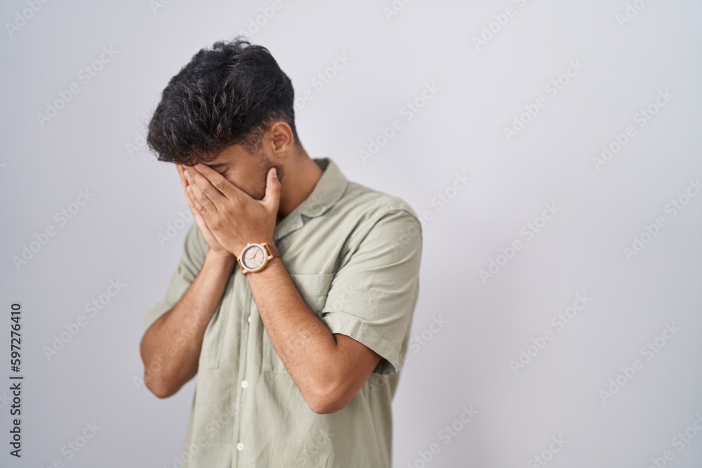 Arab man with beard standing over white background with sad expression covering face with hands while crying. depression concept. Arab man with beard standing over white background with sad expression covering face with hands while crying. depression concept.