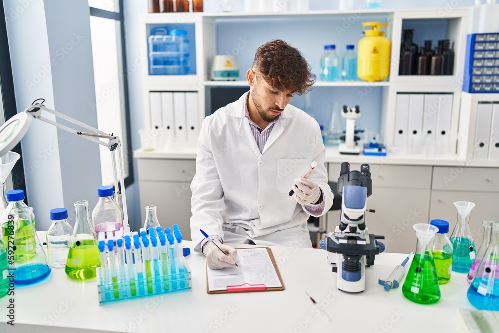 Young arab man scientist write on document analysing blood test tube at laboratory Young arab man scientist write on document analysing blood test tube at laboratory