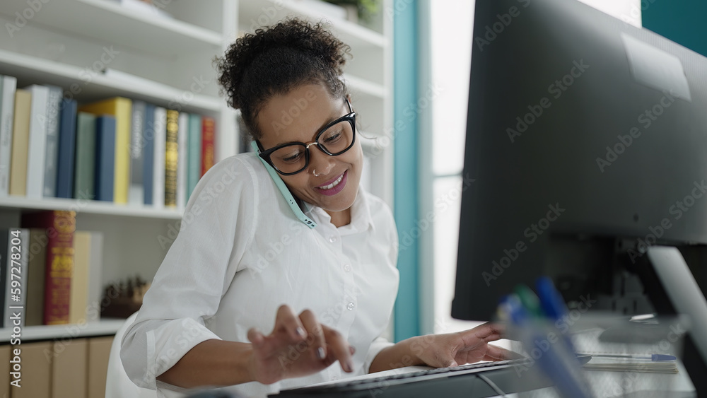 African american woman student using computer talking on smartphone at library university African american woman student using computer talking on smartphone at library university
