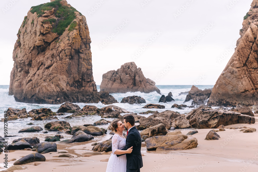 high cliffs and lots of stones in seawater. newlyweds hug and lo