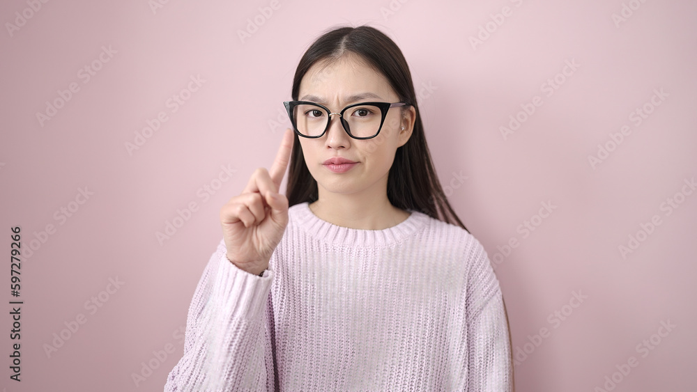 Young chinese woman doing no gesture with finger over isolated pink background Young chinese woman doing no gesture with finger over isolated pink background