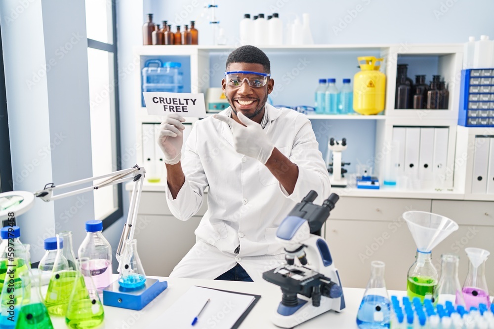 African american man working on cruelty free laboratory smiling happy pointing with hand and finger African american man working on cruelty free laboratory smiling happy pointing with hand and finger