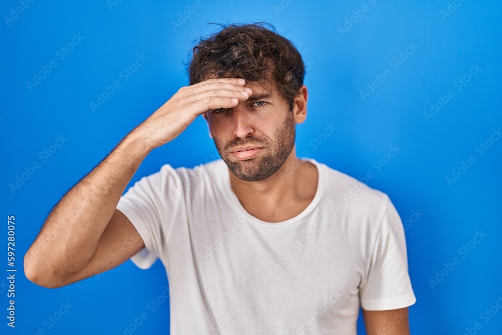 Hispanic young man standing over blue background worried and stressed about a problem with hand on forehead, nervous and anxious for crisis Hispanic young man standing over blue background worried and stressed about a problem with hand on forehead, nervous and anxious for crisis