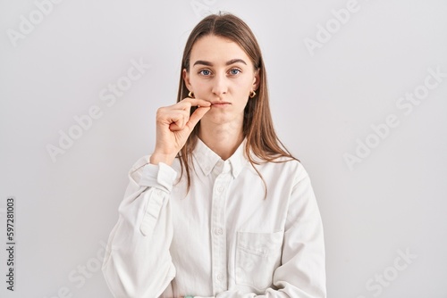 Young caucasian woman standing over isolated background mouth and lips shut as zip with fingers. secret and silent, taboo talking