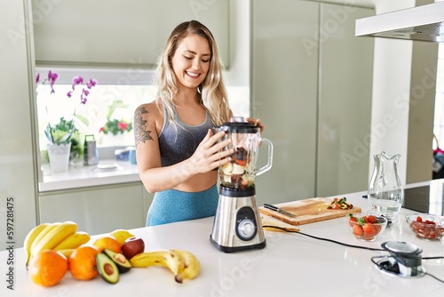 Young woman smiling confident blending healthy smoothie at kitchen