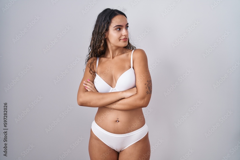 Fototapeta premium Young hispanic woman wearing white lingerie looking to the side with arms crossed convinced and confident