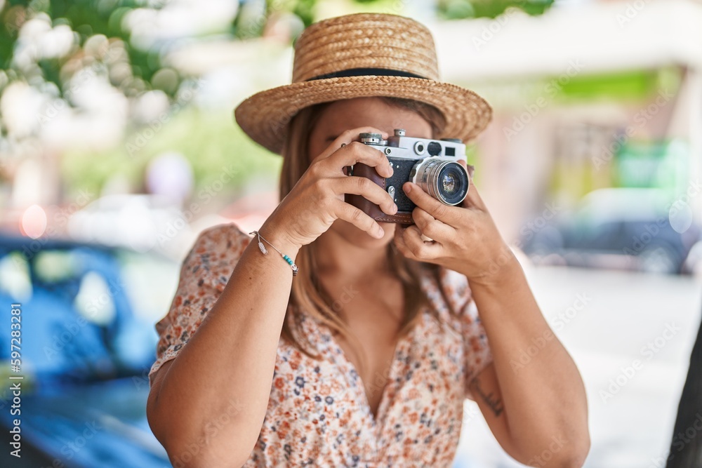 Young woman tourist wearing summer using vintage camera at street
