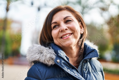 Middle age woman smiling confident looking to the side at park