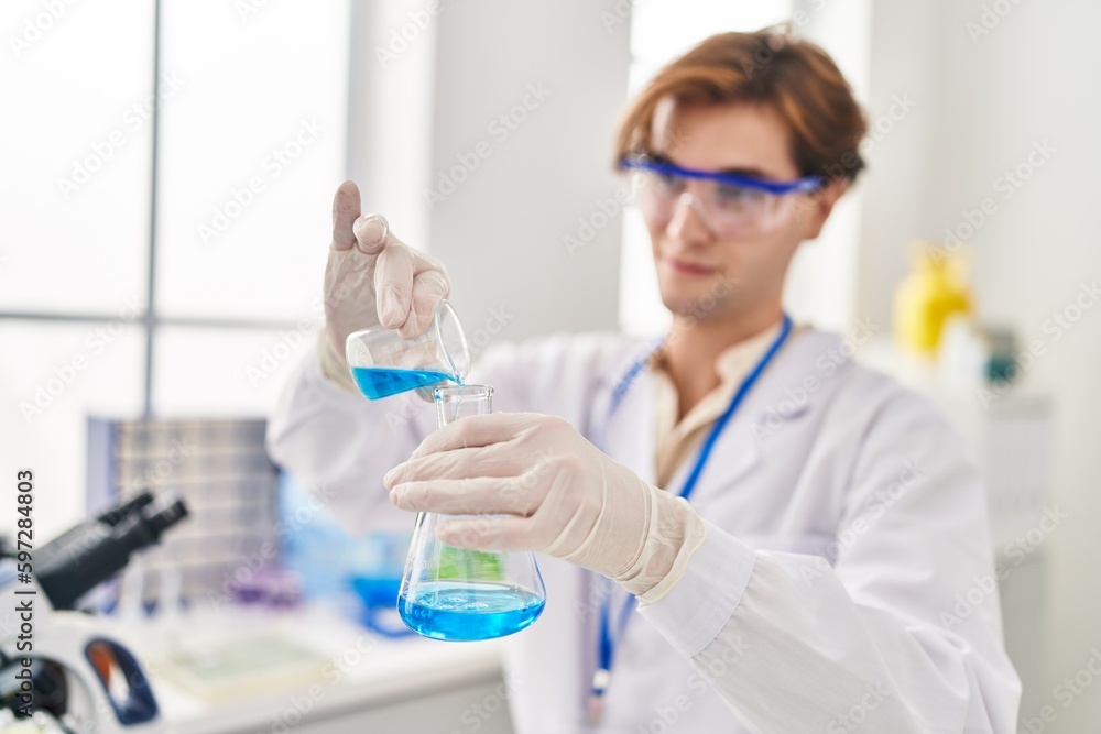 Young caucasian man scientist pouring liquid on test tube at laboratory Young caucasian man scientist pouring liquid on test tube at laboratory