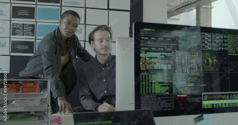 Two Engineers looking at Code on Computer Monitor in Office Two Engineers looking at Code on Computer Monitor in Office