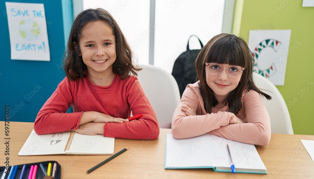Adorable girls students sitting on table smiling confident at classroom Adorable girls students sitting on table smiling confident at classroom