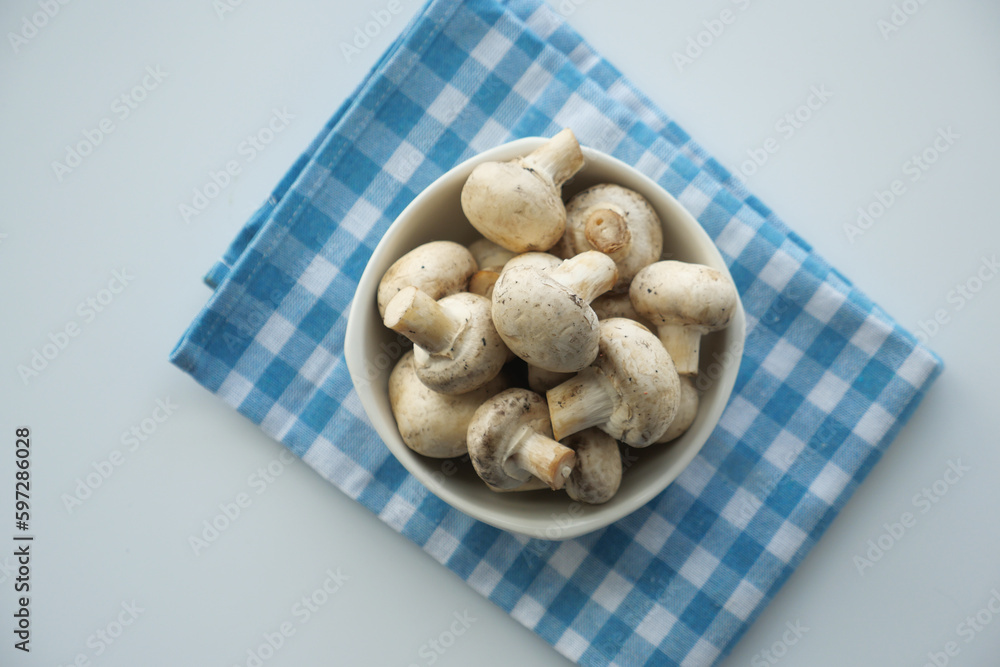 Fresh champignons mushroom in a white bowl on table Fresh champignons mushroom in a white bowl on table