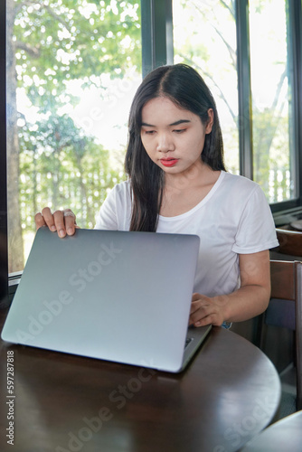 Asian woman wearing a white t-shirt a hand close or open a laptop computer, getting ready for work