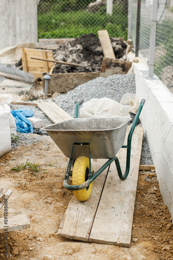Wheelbarrow on background of gravel at construction site. House building and landscaping backyard concept. Gardening work Wheelbarrow on background of gravel at construction site. House building and landscaping backyard concept. Gardening work
