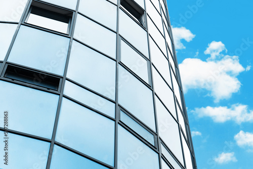 Blue glass background. Office block texture. Glass skyscraper background. Glass window building. Business building pattern. Round shape design architecture. Isolated on sky. Sunlight flare shine.