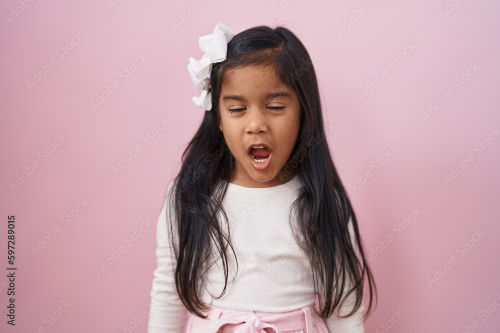 Little hispanic girl standing over pink background scared and amazed with open mouth for surprise, disbelief face Little hispanic girl standing over pink background scared and amazed with open mouth for surprise, disbelief face