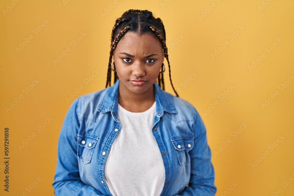 African american woman with braids standing over yellow background skeptic and nervous, frowning upset because of problem. negative person. African american woman with braids standing over yellow background skeptic and nervous, frowning upset because of problem. negative person.