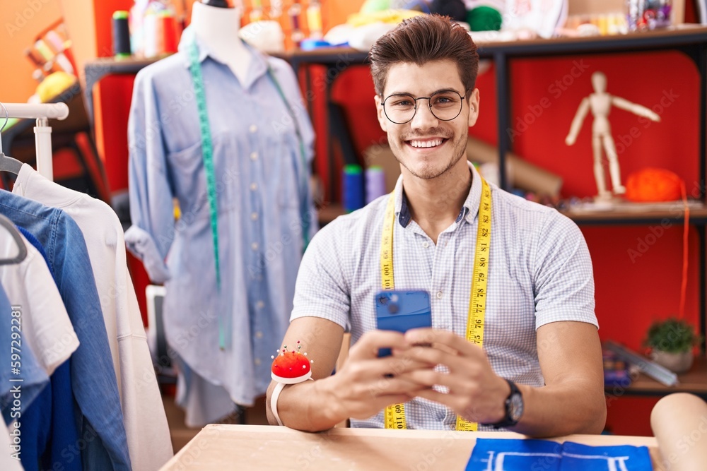 Young hispanic man tailor smiling confident using smartphone at atelier Young hispanic man tailor smiling confident using smartphone at atelier