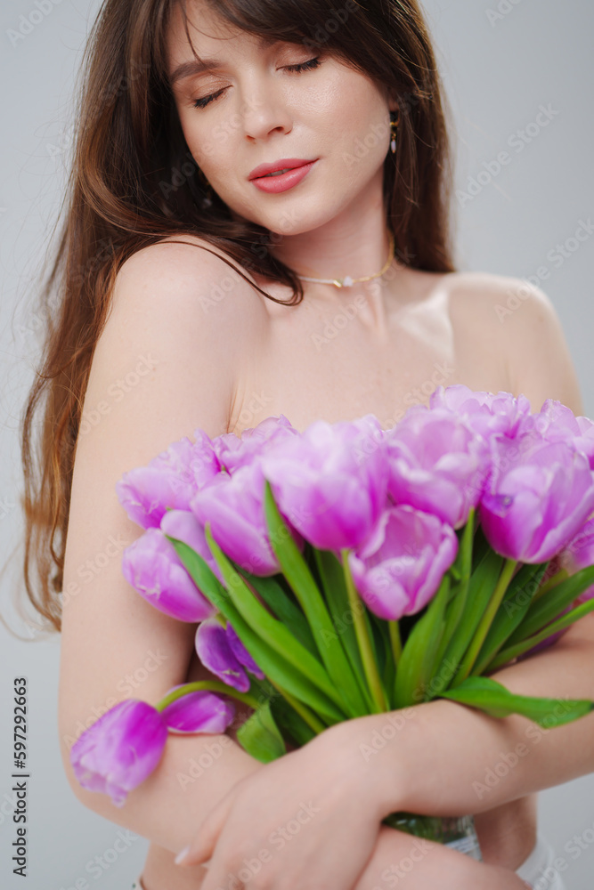 portrait of a beautiful woman topless with tulips on a white background.