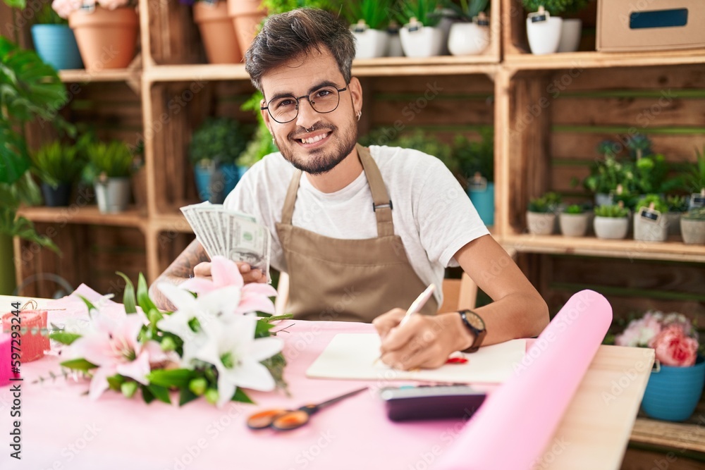 Young hispanic man florist counting dollars writing on notebook at flower shop Young hispanic man florist counting dollars writing on notebook at flower shop