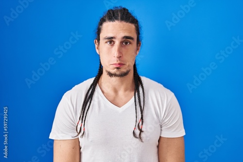 Hispanic man with long hair standing over blue background depressed and worry for distress, crying angry and afraid. sad expression.