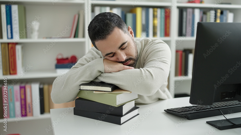 Young hispanic man student sleeping with head on books at library university Young hispanic man student sleeping with head on books at library university