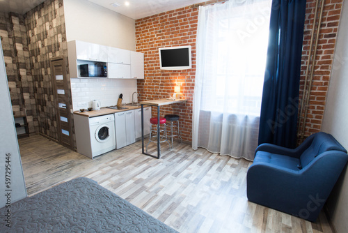 Slika na platnu This image shows a modern, compact studio apartment or hotel room with an open-plan layout